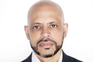 A headshot of Marc Chennault, a Black man with a medium skin tone, shaved head, and a close-cropped black beard.
