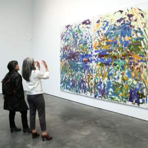 Artist Tomie Arai and Kay Takeda face a large diptych painting by Joan Mitchell in David Zwirner gallery