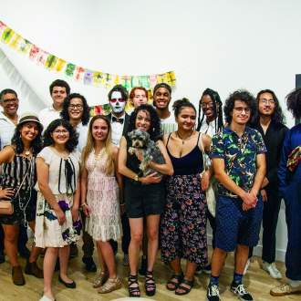 Group of young artists in a gallery space with artwork behind them
