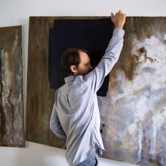 Artist Wojciech Gilewicz carrying a large abstract painting