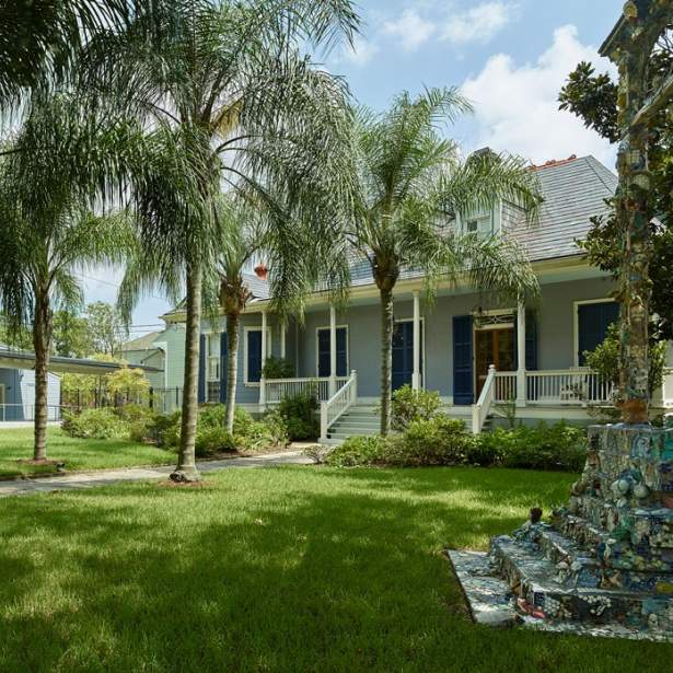 A green lawn and row of palm trees leads to the main house of Joan Mitchell Center, with another long building in background