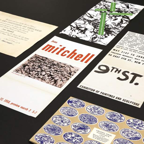 Various papers and posters on a table, including visible text "Joan Mitchell" and "9th St. Exhibition"